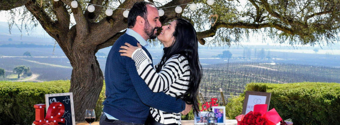 Casal comemorando o amor e a felicidade diante de uma linda vista do vinhedo no Chile
