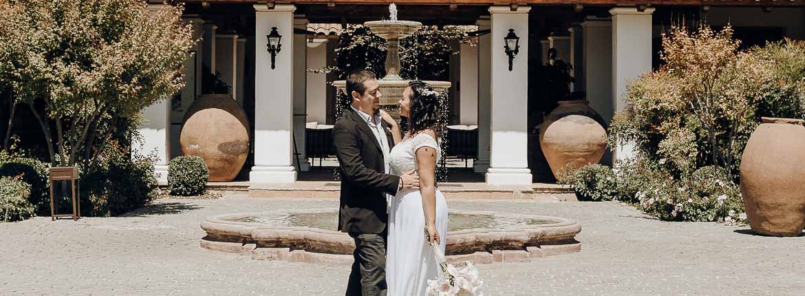 O casal, abraçados, felizes em frente ao vinhedo.