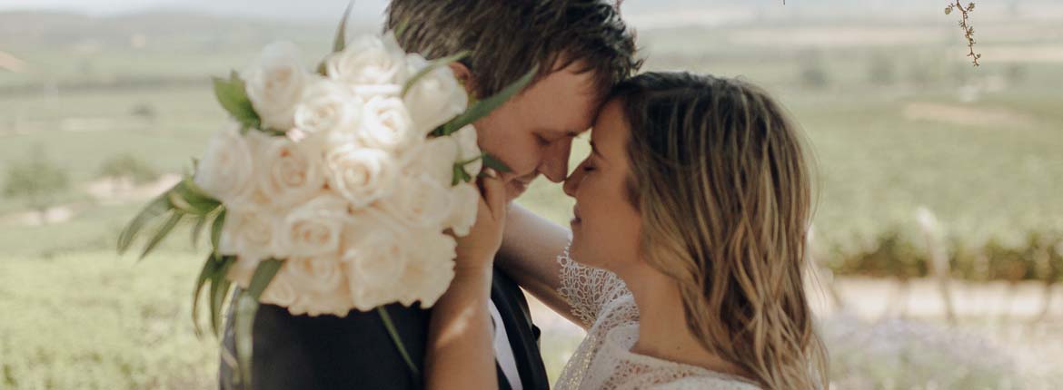 Noivos estão de frente um para outro, com rostos bem próximos, quase se beijando