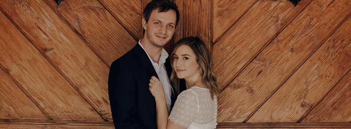 The bride and groom are cuddled in front of a beautiful solid wood door.