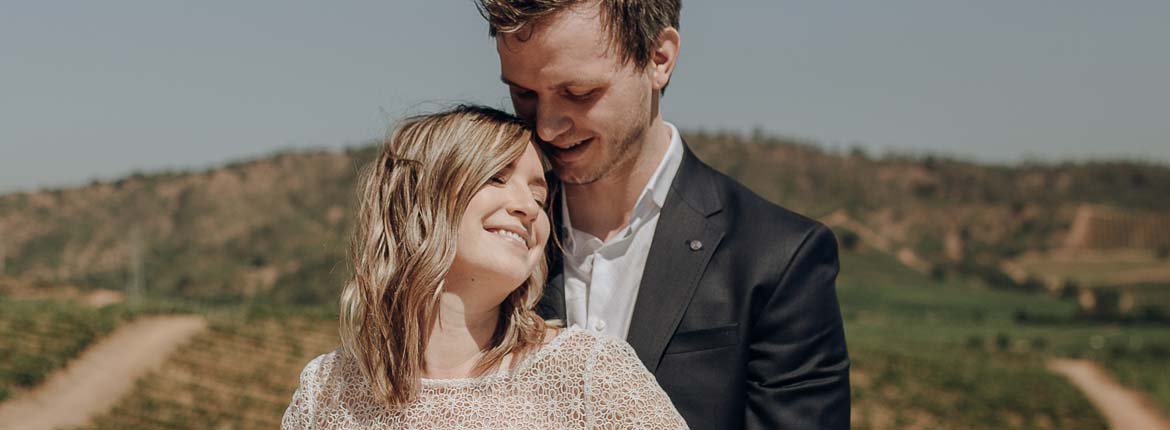 Grooms are together, smiling, with the view of the valley behind them