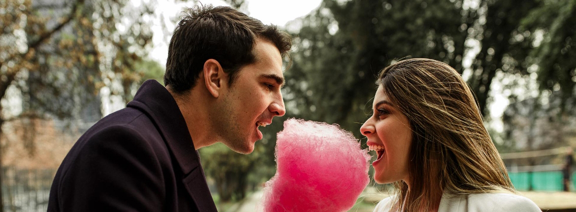 Casal degustando um algodão doce rosa.